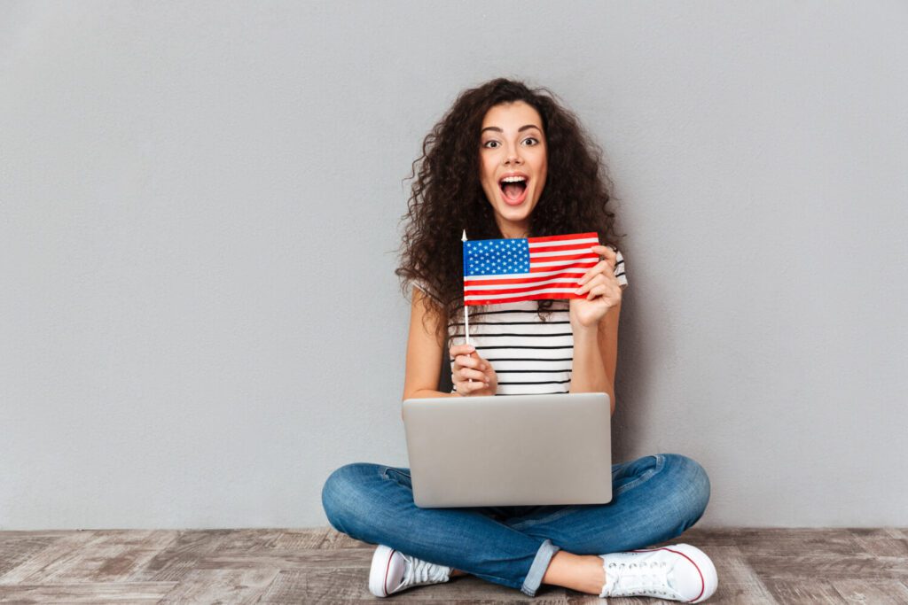 Studentessa con computer portatile e bandiera americana, simbolo dell'abstract della tesi in inglese richiesto in alcuni corsi