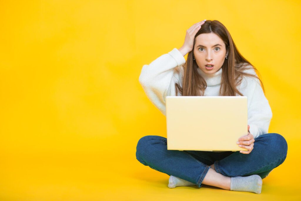 Studentessa sorpresa davanti al computer mentre scopre come scrivere l'abstract della tesi