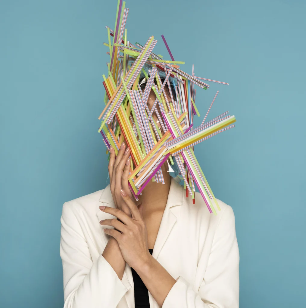 Donna con il volto coperto da cannucce colorate come metafora dello stress e della confusione nella scrittura della tesi magistrale