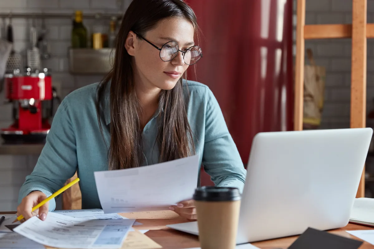 Studentessa che confronta il report antiplagio su carta con il testo della tesi aperto sul computer